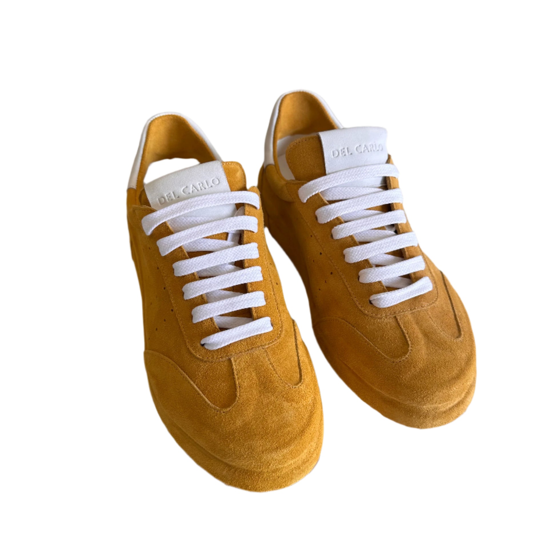 Pair of tan sneakers with white laces on a light surface