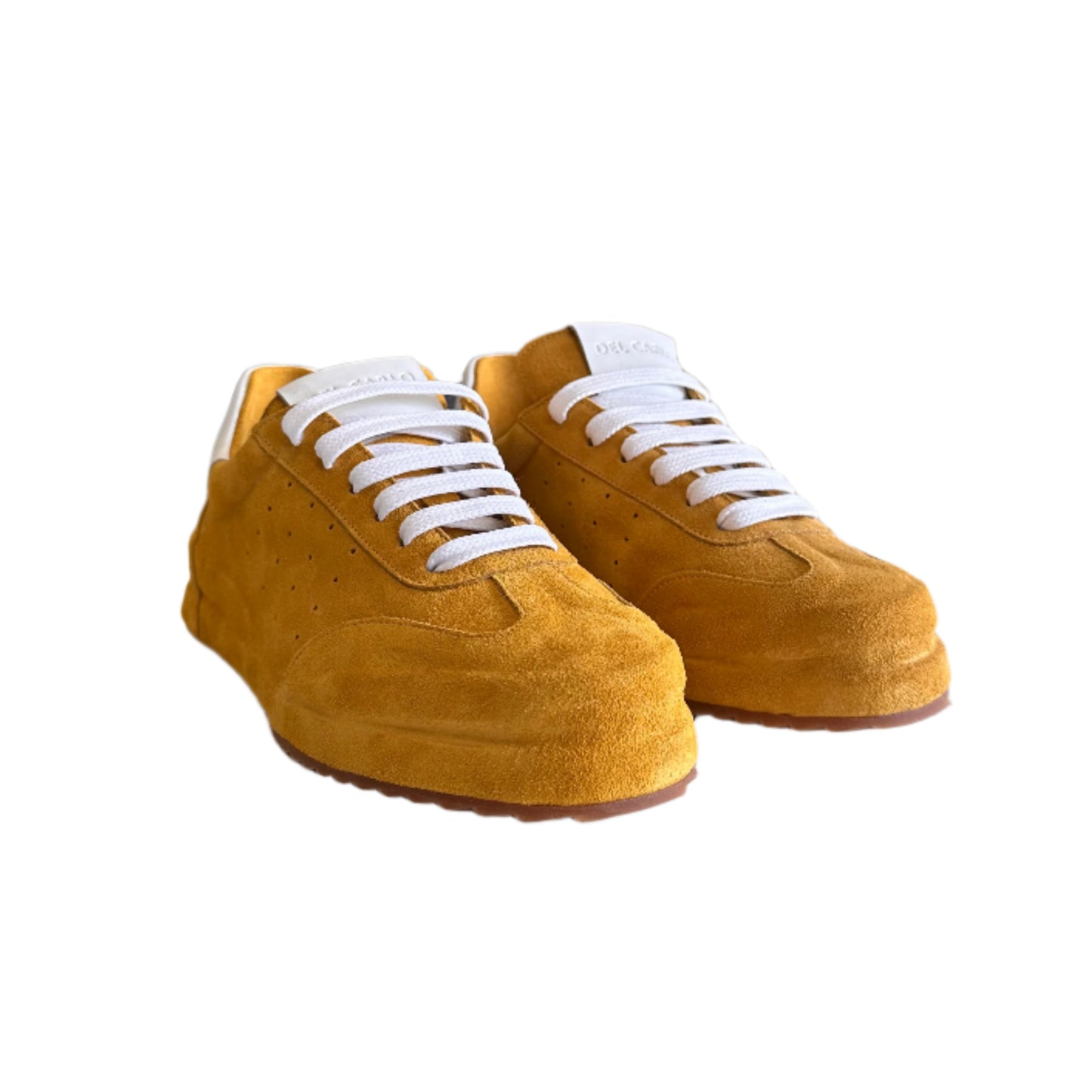Yellow sneakers with white laces on a white surface, with a blurred indoor background.