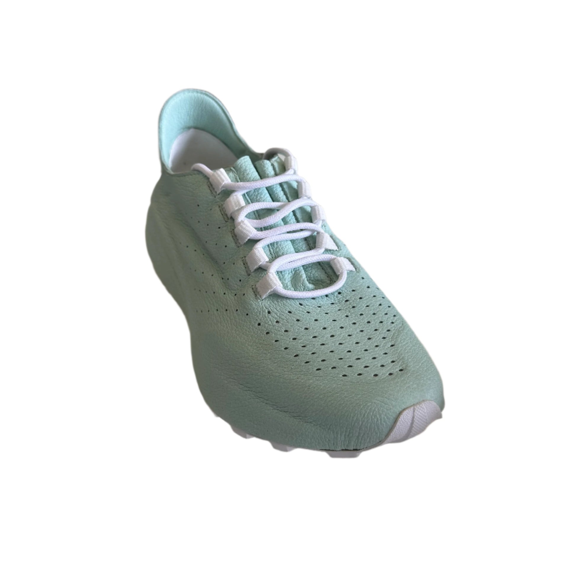 Green sneaker on a white surface with a blurred indoor background