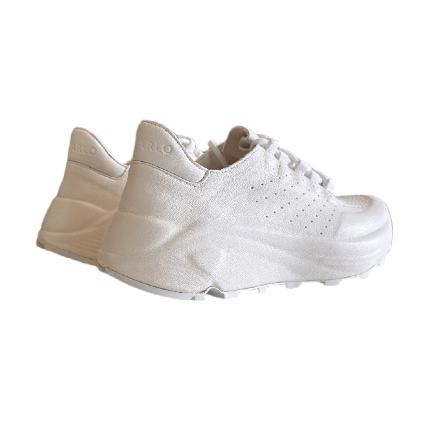 White sneakers hanging on a white wall with a blurred indoor background