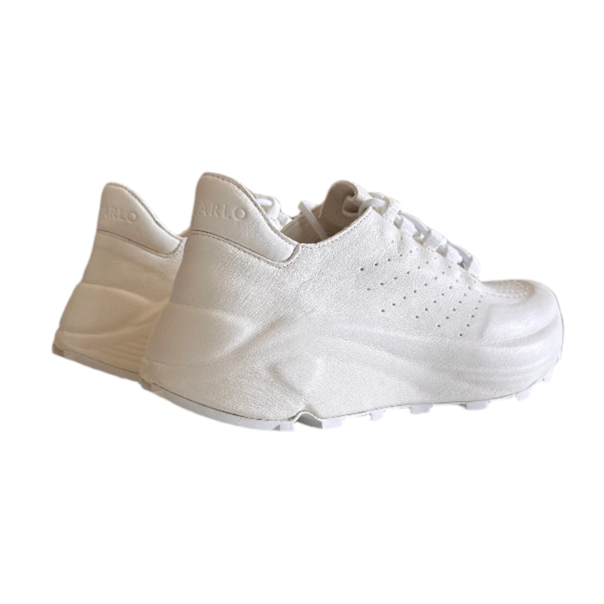 White sneakers hanging on a white wall with a blurred indoor background
