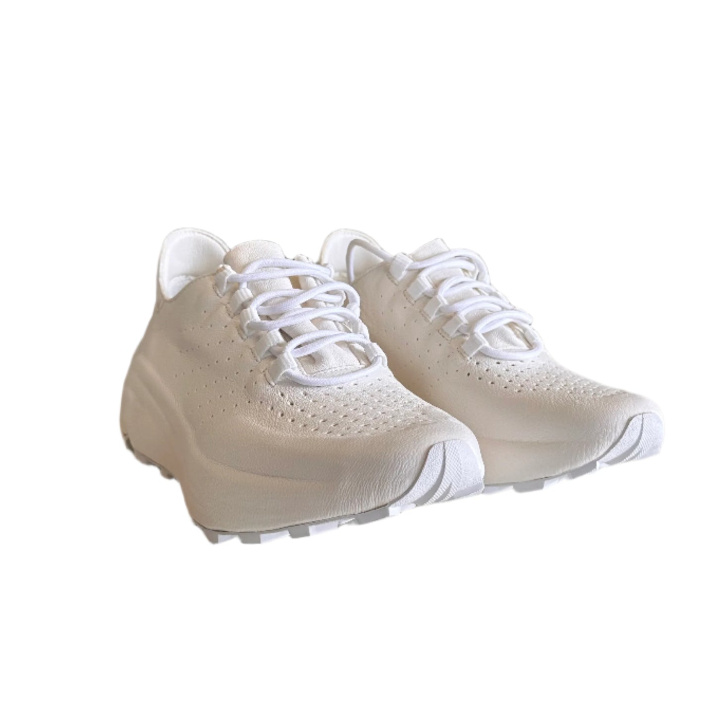 White sneakers on a white surface with a cluttered room in the background