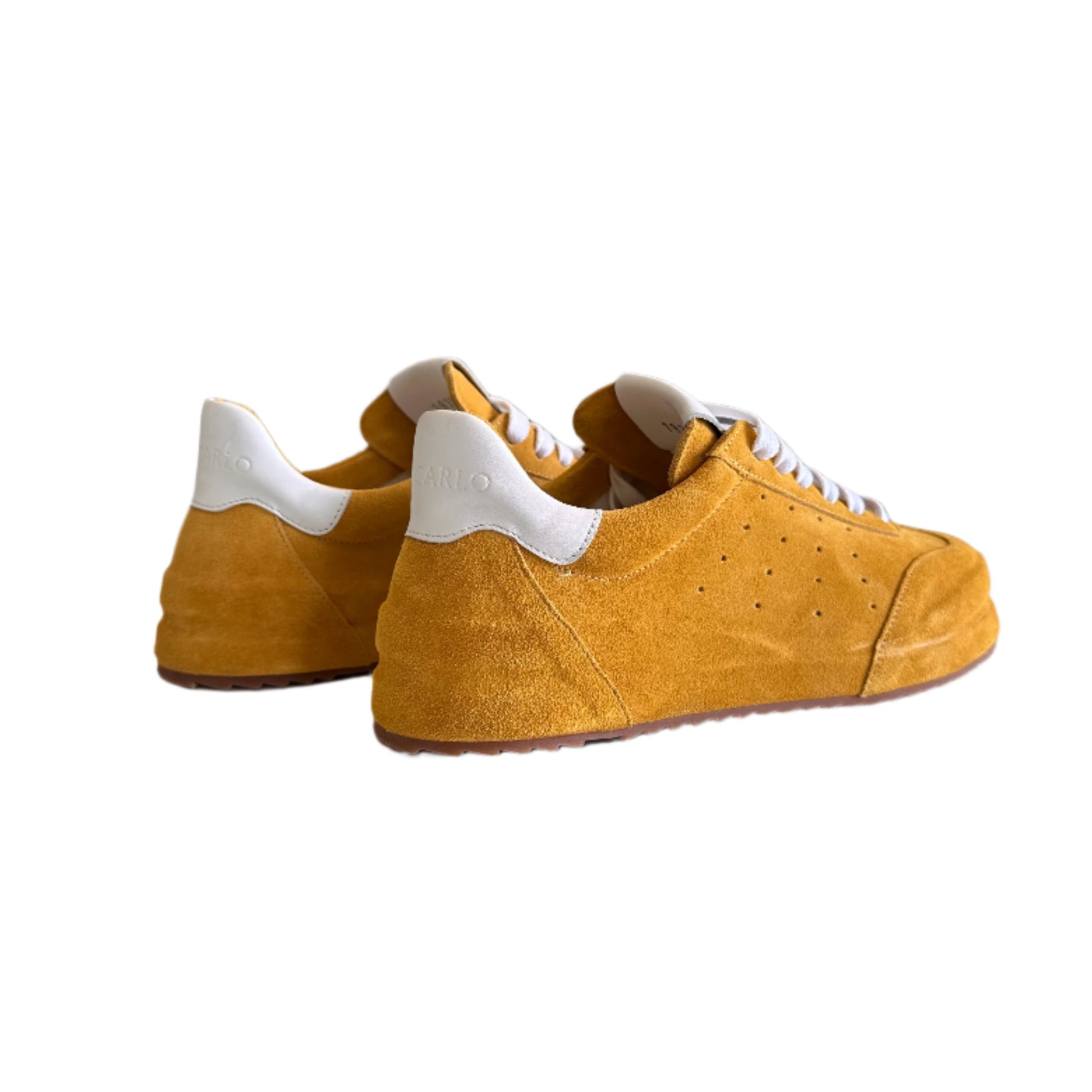 Yellow sneakers with white soles hanging on a white wall