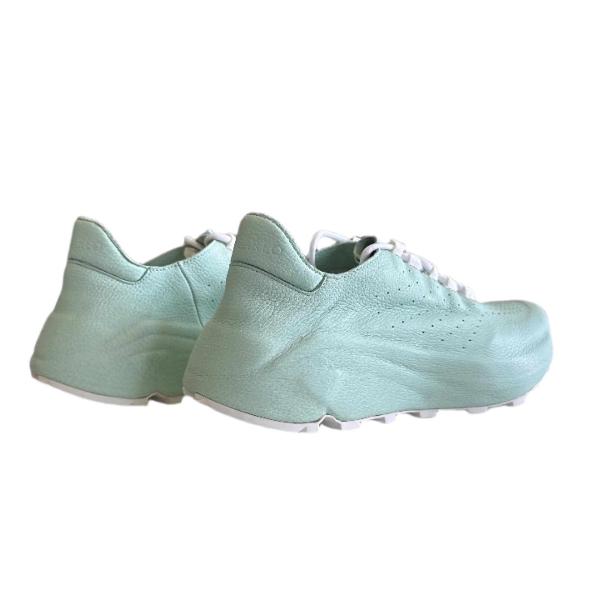 Light blue sneaker hanging on a white surface with a blurred background
