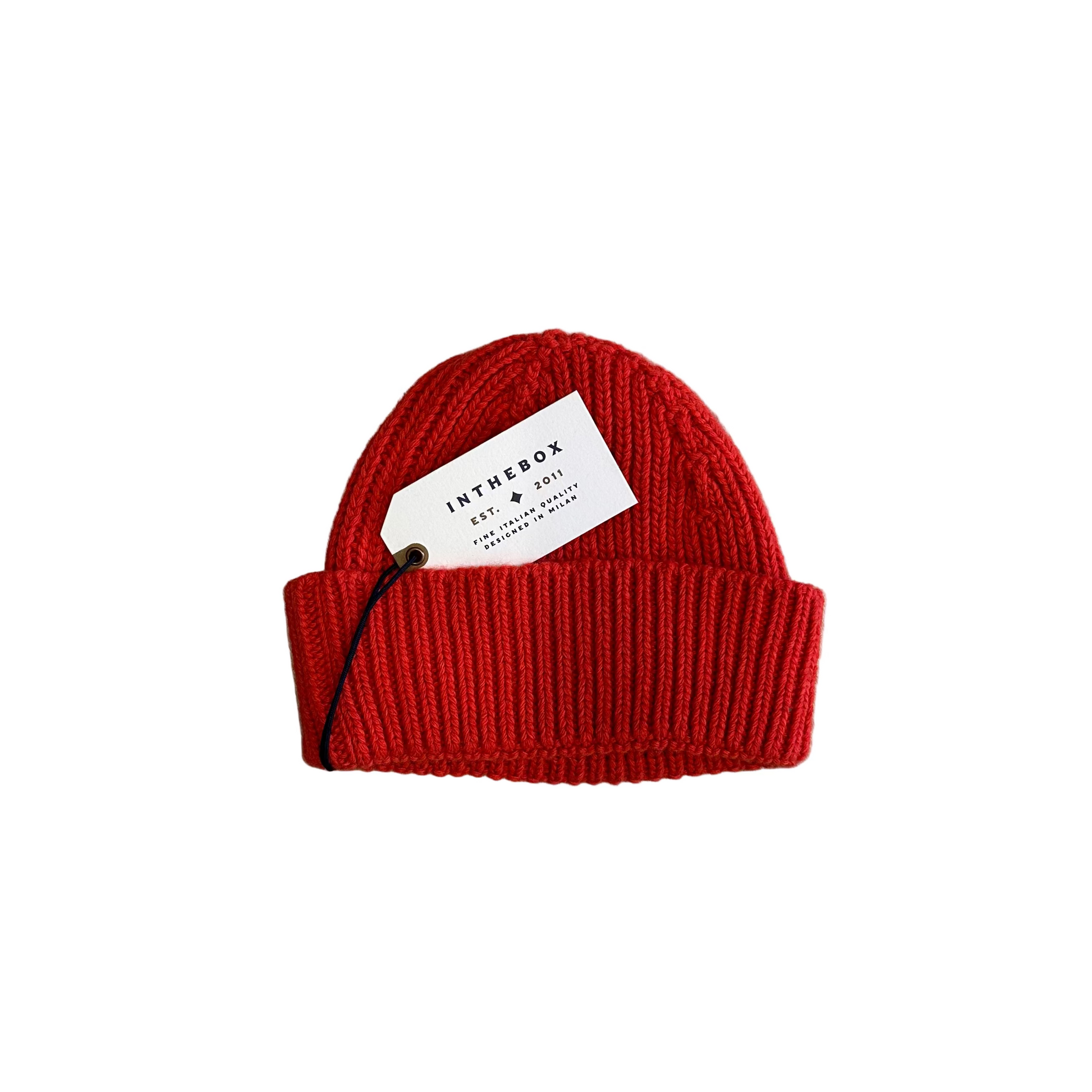 Red knit beanie with a tag on a wooden floor