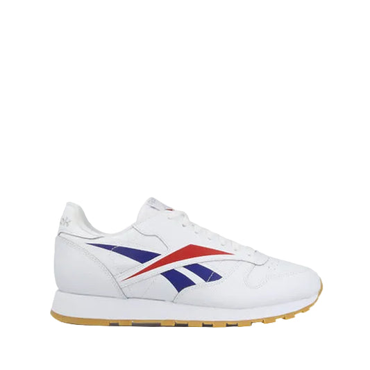A white Reebok Classic Leather sneaker with red and blue vector logos on a white background.